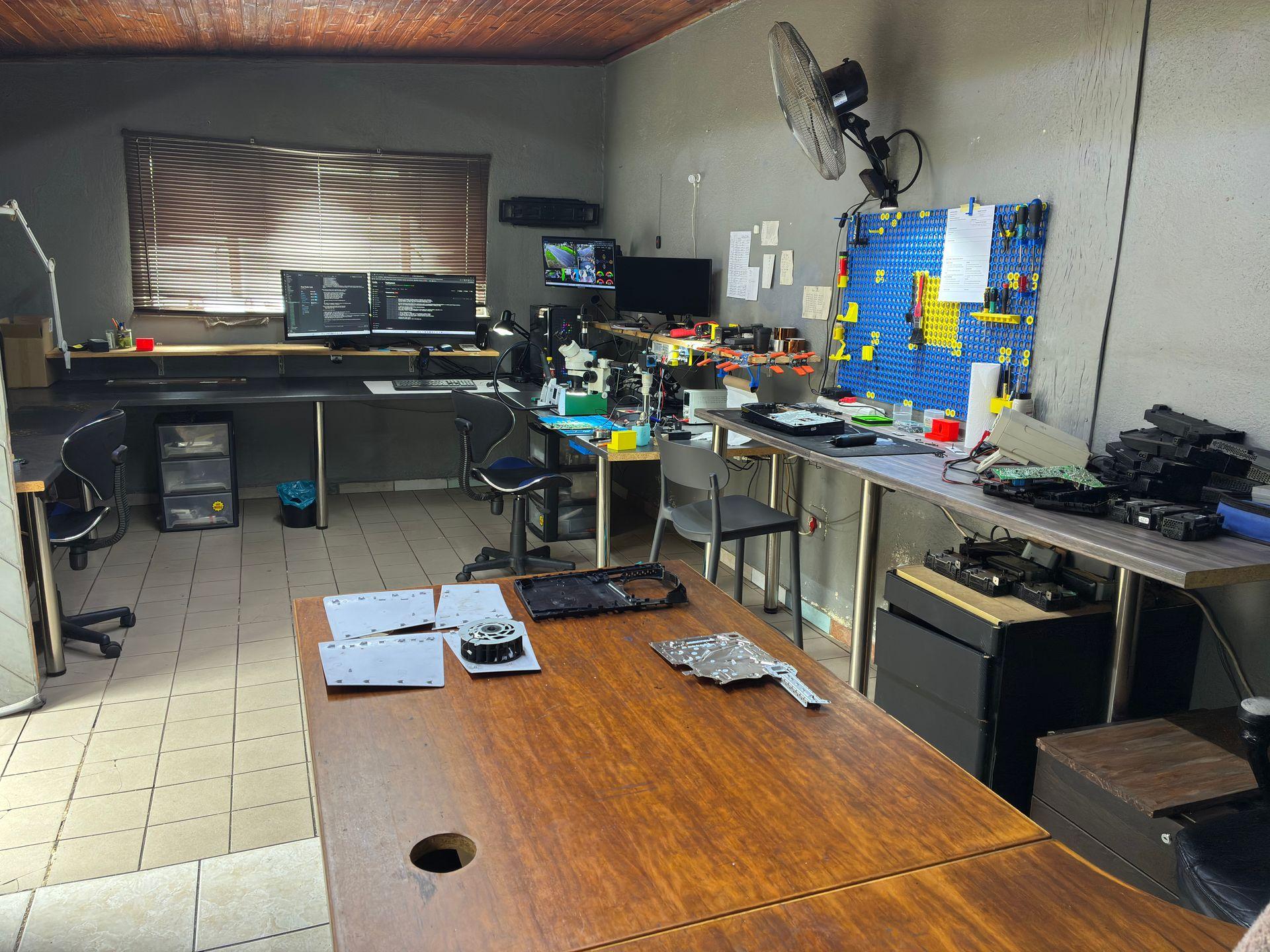 Console Service Centre full workshop with multiple repair workstations, blue pegboard tool wall and consoles being repaired